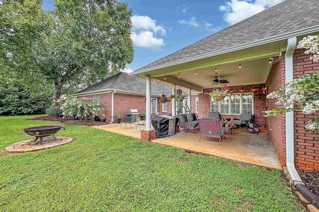 view of yard with ceiling fan, a fire pit, and a patio