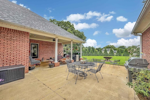 view of patio / terrace featuring ceiling fan, a grill, and an outdoor brick fireplace