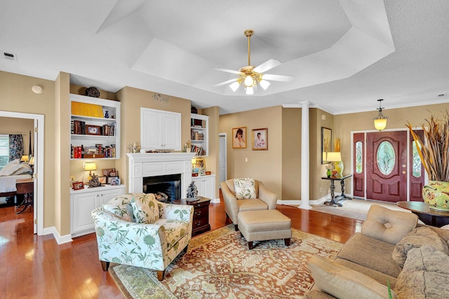 living room featuring decorative columns, ceiling fan, hardwood / wood-style flooring, and built in shelves