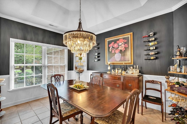 dining space with crown molding, light tile patterned floors, a notable chandelier, and a tray ceiling