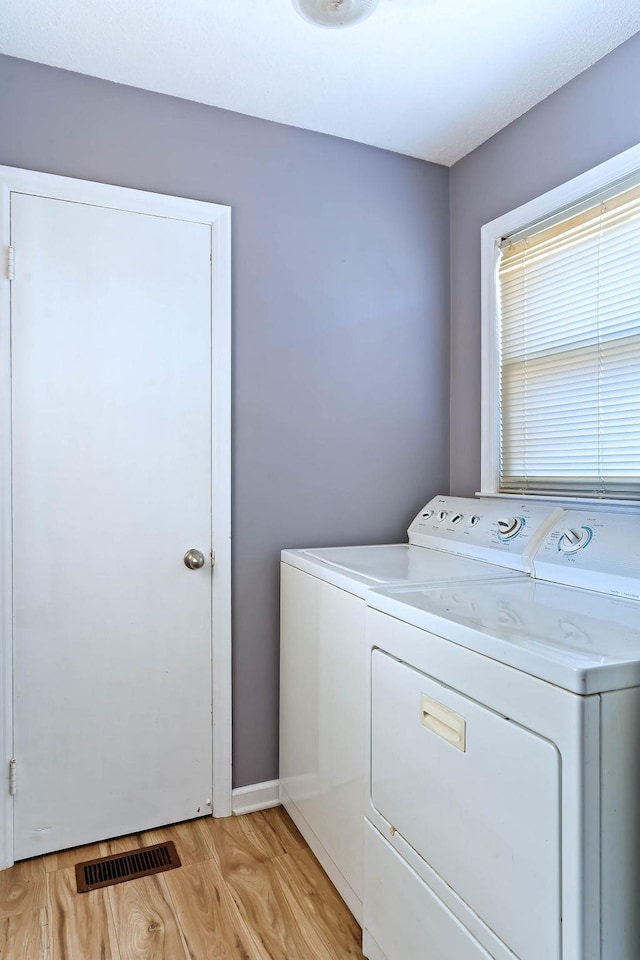 clothes washing area featuring separate washer and dryer and light wood-type flooring