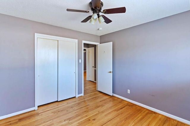 unfurnished bedroom featuring ceiling fan, light hardwood / wood-style floors, a textured ceiling, and a closet