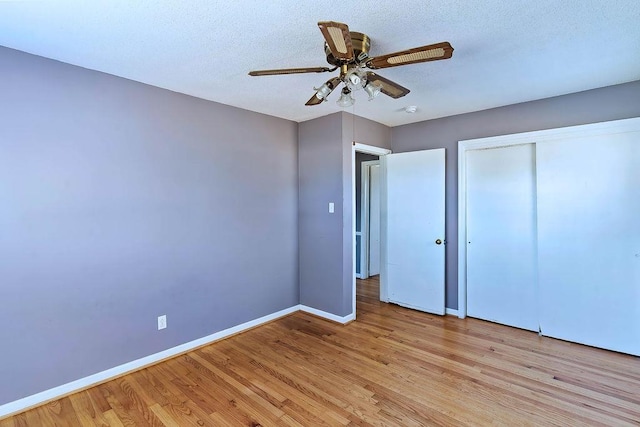 unfurnished bedroom with ceiling fan, a closet, a textured ceiling, and light hardwood / wood-style flooring