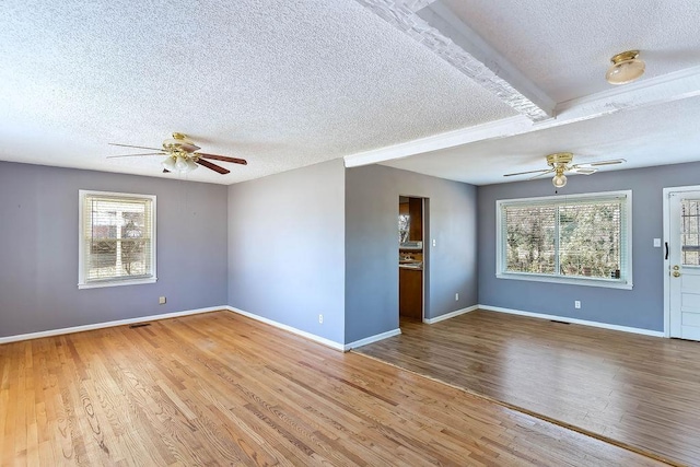 unfurnished living room featuring plenty of natural light, a textured ceiling, and hardwood / wood-style flooring