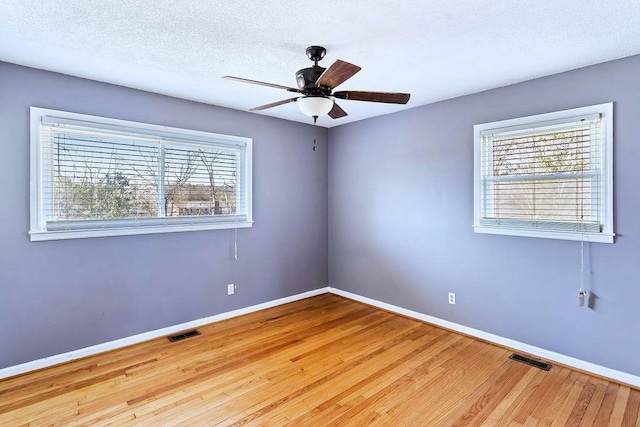 spare room featuring light wood-type flooring, ceiling fan, and a textured ceiling