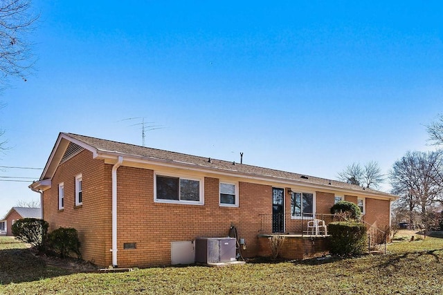 rear view of house featuring central air condition unit and a lawn