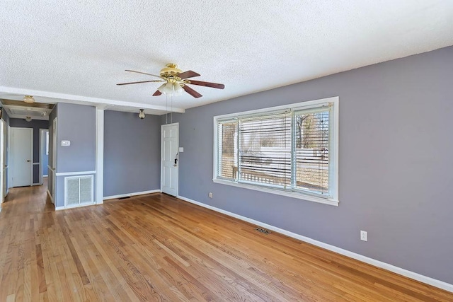 empty room with ceiling fan, a textured ceiling, and light wood-type flooring