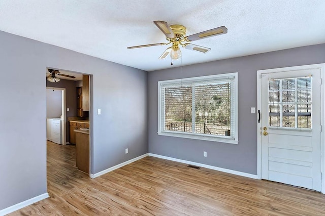 interior space featuring light wood-type flooring, a textured ceiling, and a healthy amount of sunlight