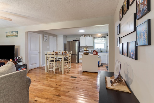 living room featuring a textured ceiling, light wood-type flooring, and sink