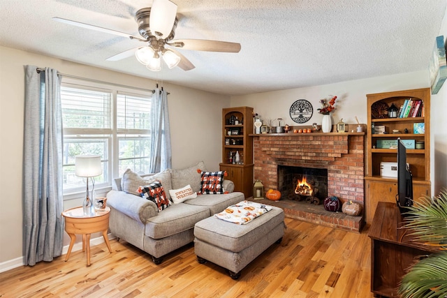 living room with a textured ceiling, a fireplace, a wealth of natural light, and light hardwood / wood-style floors