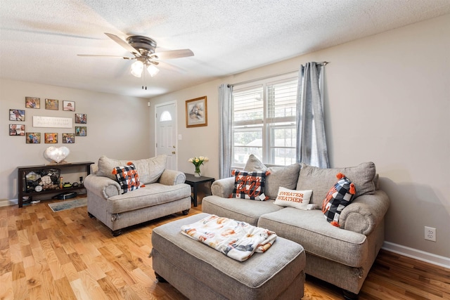 living room with ceiling fan, a textured ceiling, and hardwood / wood-style flooring