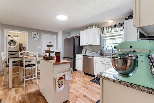 kitchen featuring sink, white cabinets, appliances with stainless steel finishes, and stacked washing maching and dryer