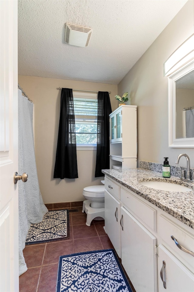 bathroom featuring a textured ceiling, tile patterned floors, vanity, and toilet