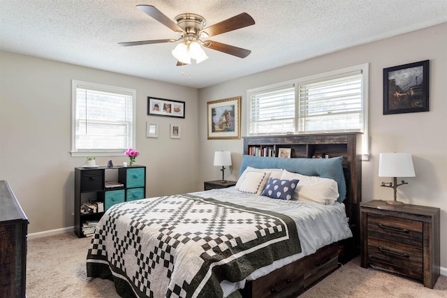 bedroom featuring ceiling fan, light colored carpet, multiple windows, and a textured ceiling