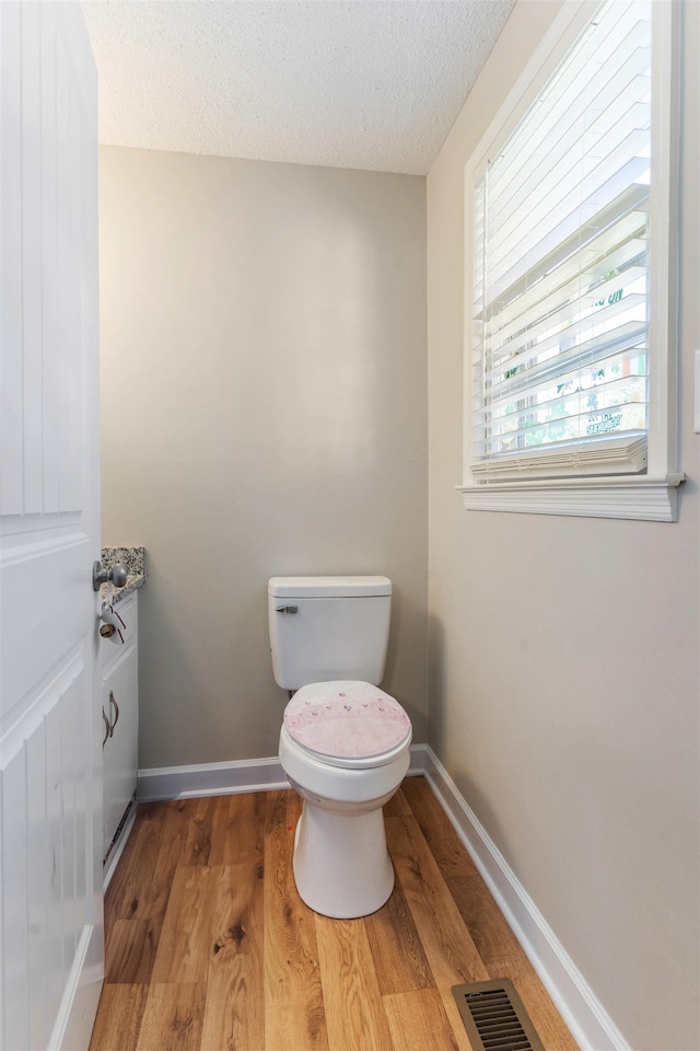 bathroom featuring toilet, a textured ceiling, and wood-type flooring