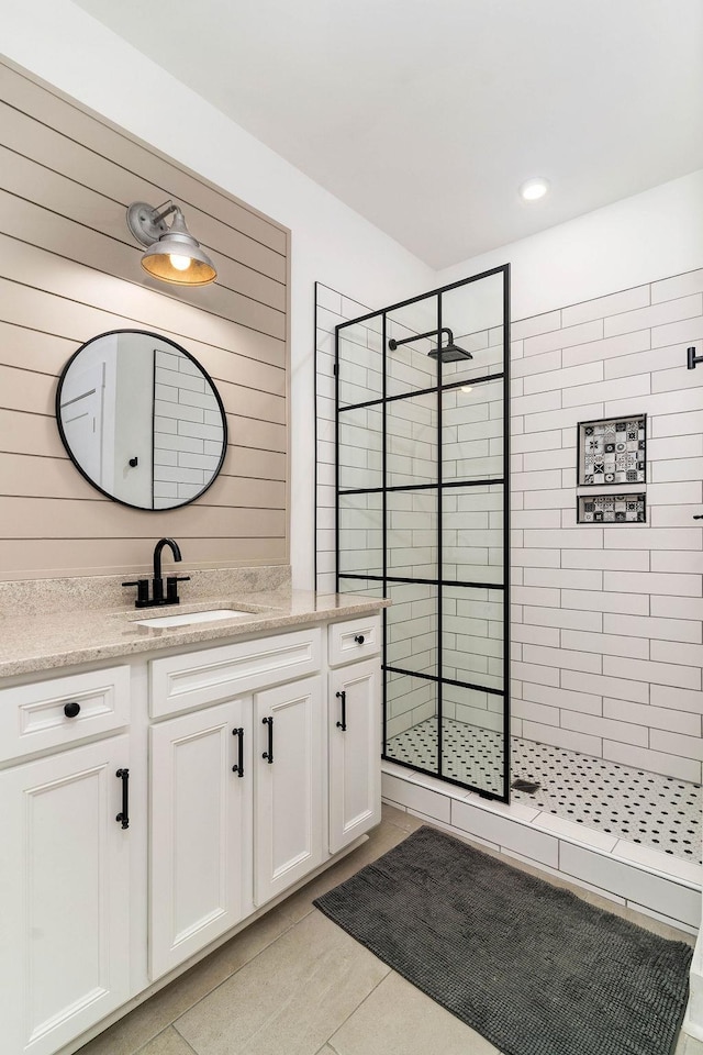 bathroom with tile patterned floors, vanity, and tiled shower