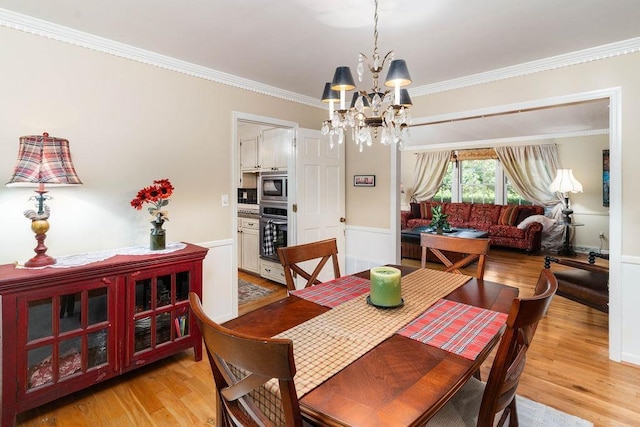 dining space featuring crown molding, a chandelier, and light hardwood / wood-style flooring