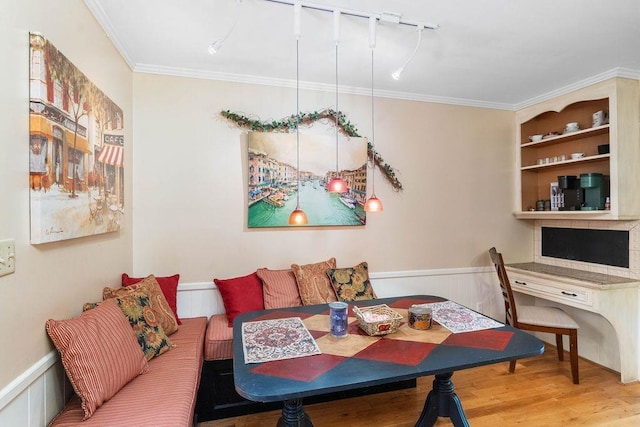 dining space featuring wood-type flooring, built in features, ornamental molding, and breakfast area