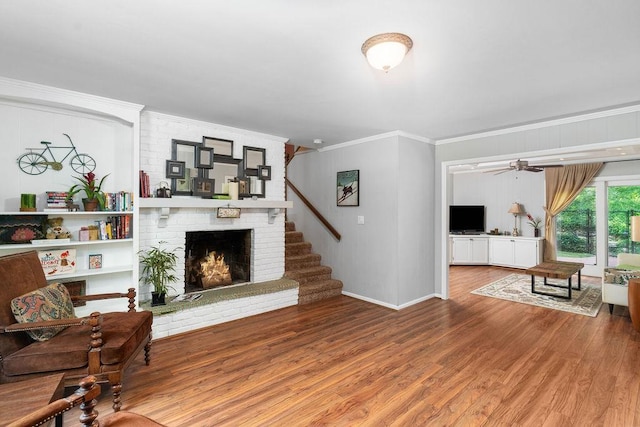 living room featuring ceiling fan, a fireplace, crown molding, and hardwood / wood-style flooring