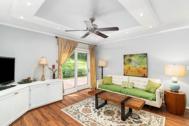 living room with light hardwood / wood-style flooring, ornamental molding, and a raised ceiling