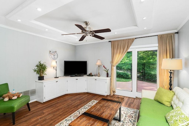 living room featuring ceiling fan, dark wood-type flooring, ornamental molding, and a raised ceiling