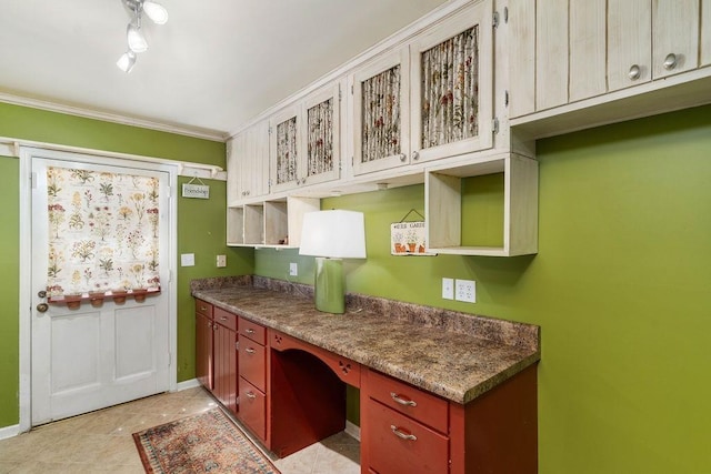 kitchen with light tile patterned floors, ornamental molding, built in desk, and stone countertops