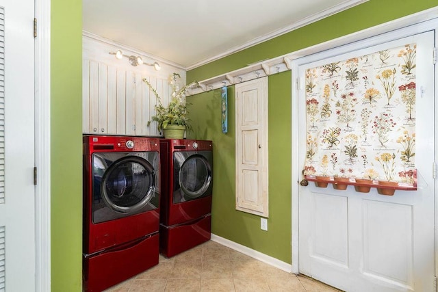 clothes washing area with washing machine and dryer, light tile patterned flooring, crown molding, and cabinets