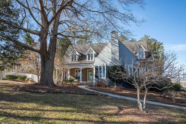 new england style home featuring covered porch and a front lawn