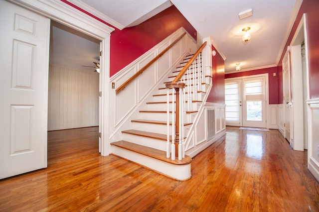 stairs with hardwood / wood-style floors, crown molding, and ceiling fan