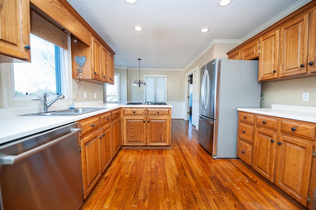 kitchen with pendant lighting, sink, stainless steel appliances, crown molding, and dark wood-type flooring