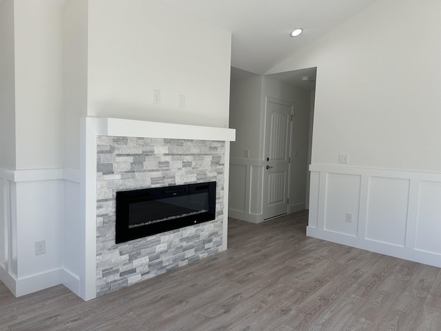 unfurnished living room with light wood-type flooring, a fireplace, and lofted ceiling