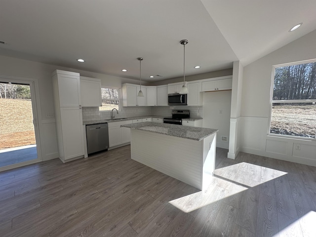 kitchen with hanging light fixtures, white cabinetry, a center island, lofted ceiling, and stainless steel appliances