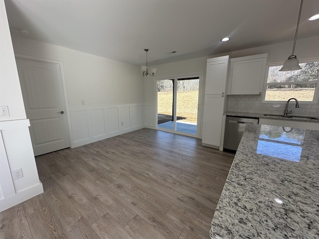 kitchen featuring sink, stainless steel dishwasher, decorative light fixtures, and white cabinetry