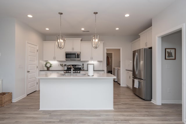 kitchen with pendant lighting, white cabinets, a center island with sink, and stainless steel appliances