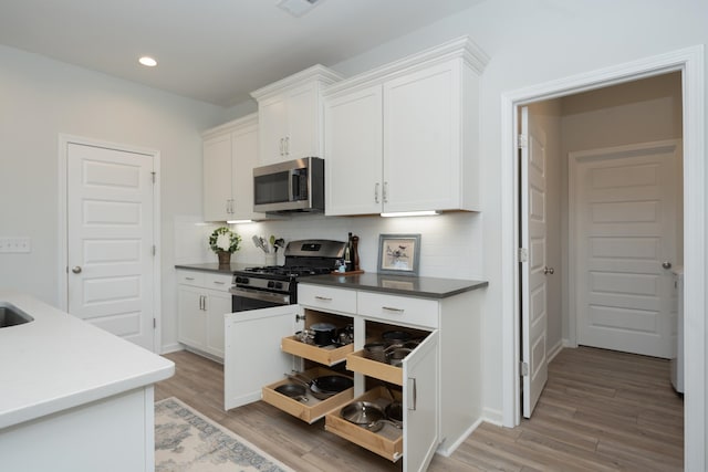 kitchen with tasteful backsplash, light wood-type flooring, stainless steel appliances, and white cabinetry