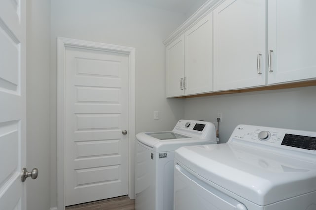 laundry area with cabinets, washer and dryer, and wood-type flooring