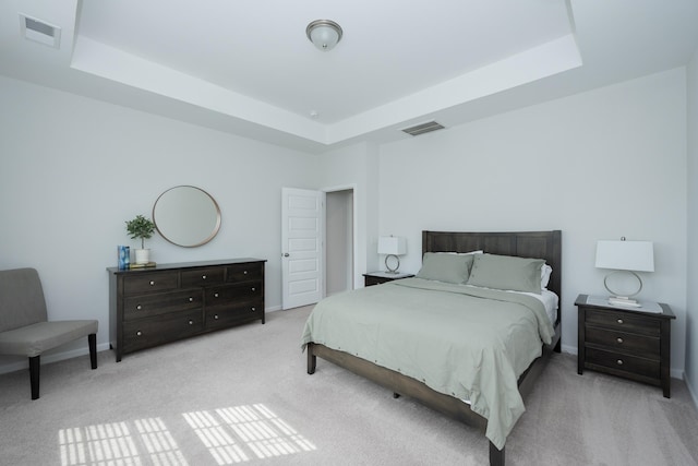 bedroom with light colored carpet and a tray ceiling