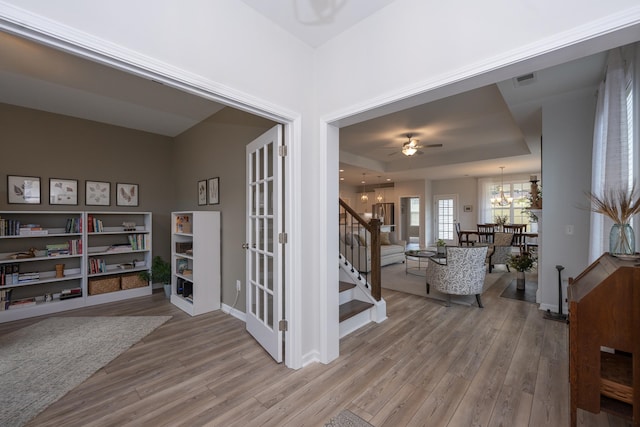 interior space with a raised ceiling, wood-type flooring, and a chandelier