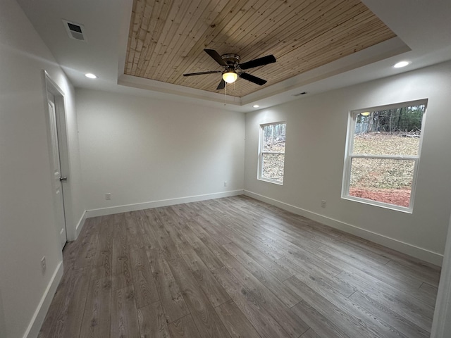 spare room featuring light wood-type flooring, ceiling fan, wood ceiling, and a tray ceiling