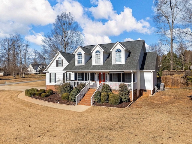 new england style home featuring a front lawn, a porch, and central AC unit