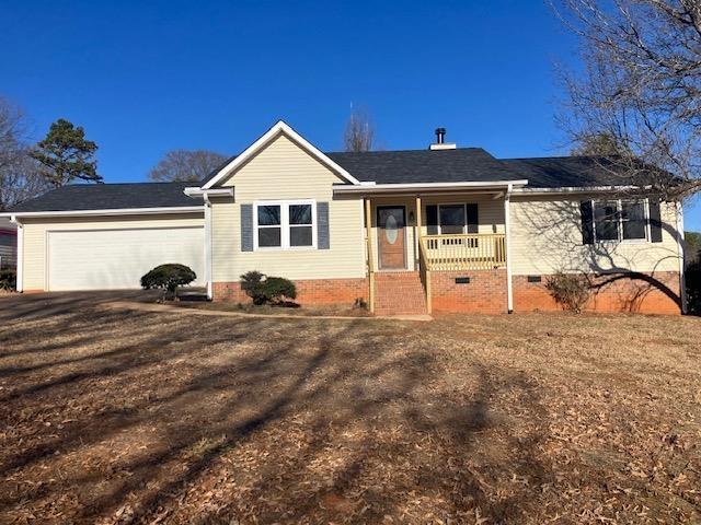 ranch-style home with a garage, a front yard, and a porch