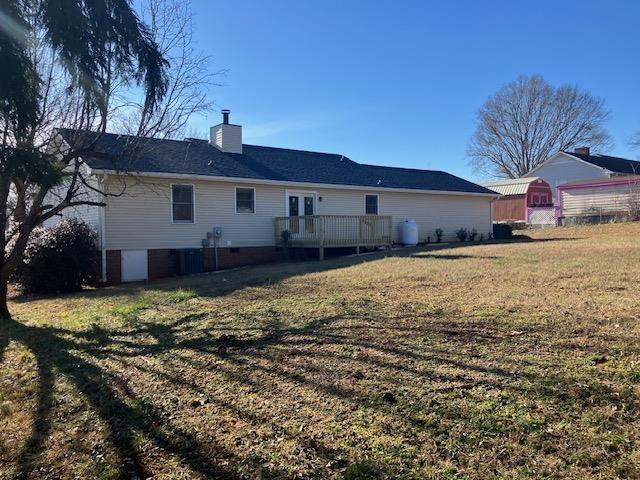 back of house featuring a wooden deck and a yard