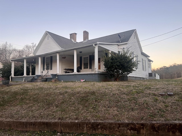 back house at dusk featuring covered porch