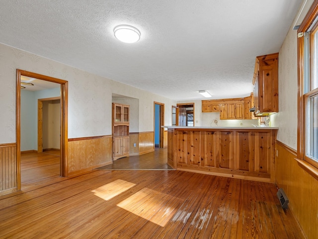 kitchen with kitchen peninsula, a textured ceiling, and hardwood / wood-style floors