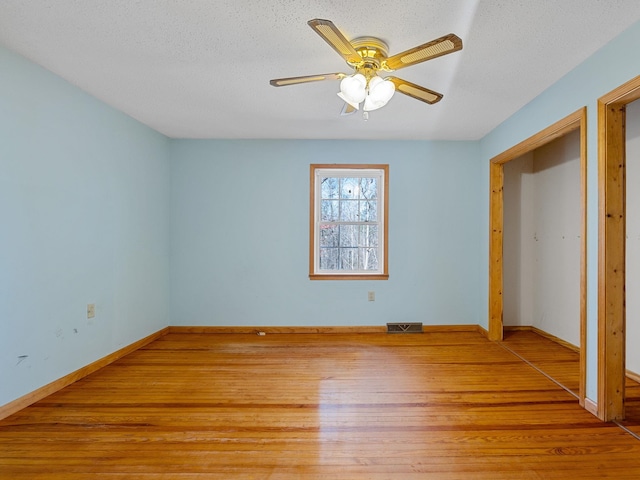 unfurnished bedroom with ceiling fan, wood-type flooring, and a textured ceiling