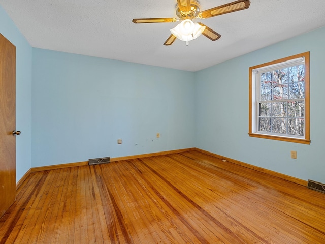 empty room with ceiling fan, wood-type flooring, and a textured ceiling