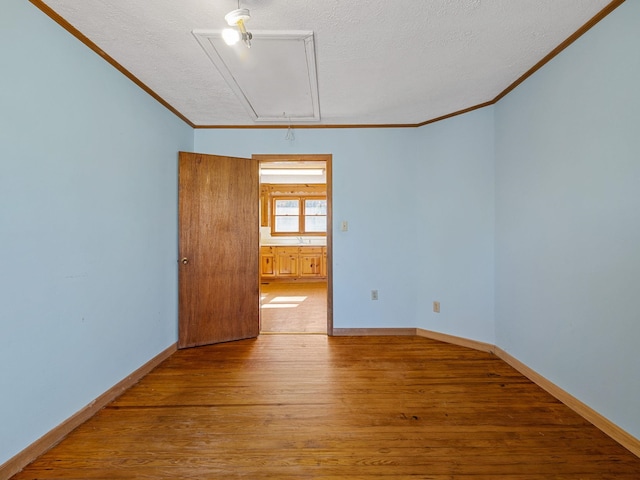 spare room with hardwood / wood-style floors, ornamental molding, and a textured ceiling