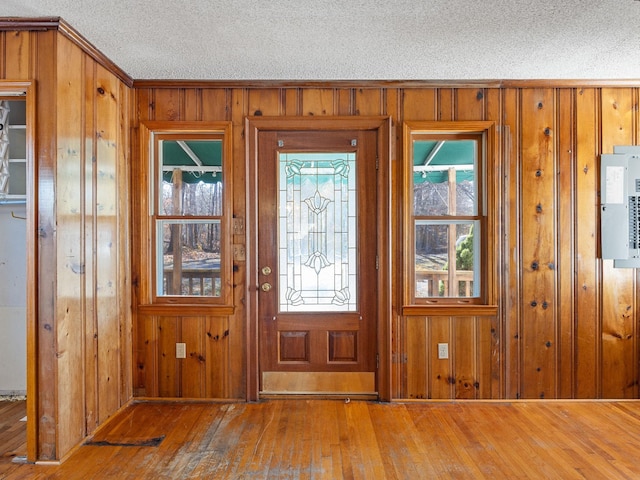 entryway with wood-type flooring, wood walls, and a textured ceiling