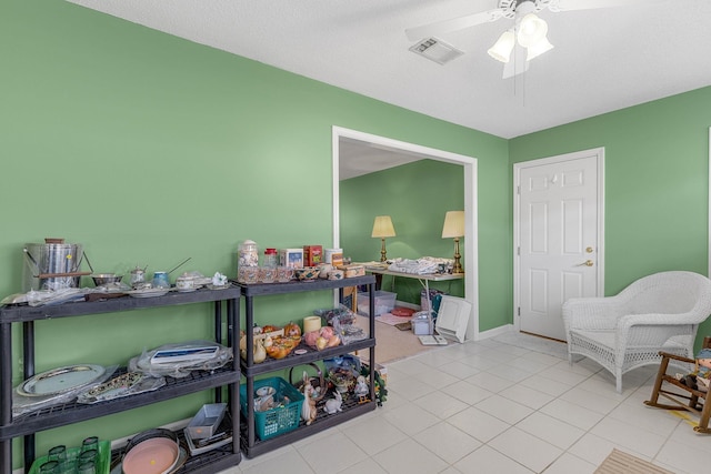 recreation room with ceiling fan, light tile patterned flooring, and a textured ceiling