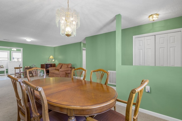 carpeted dining room featuring a textured ceiling and an inviting chandelier